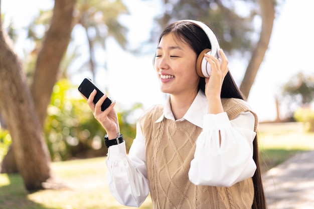 Mooie Chinese vrouw buitenshuis met behulp van mobiele telefoon