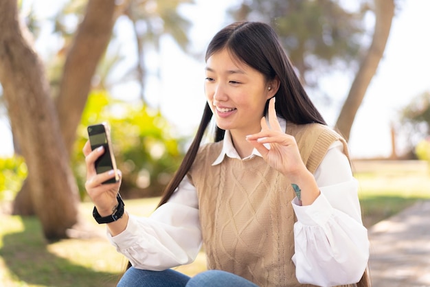 Mooie chinese vrouw buitenshuis met behulp van mobiele telefoon