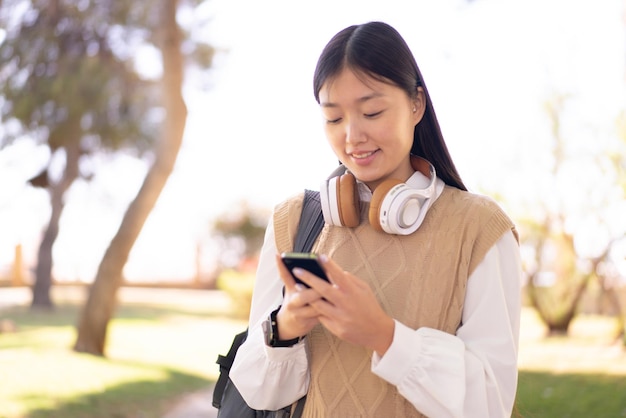 Mooie Chinese vrouw buitenshuis met behulp van mobiele telefoon