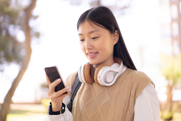 Mooie Chinese vrouw buitenshuis met behulp van mobiele telefoon