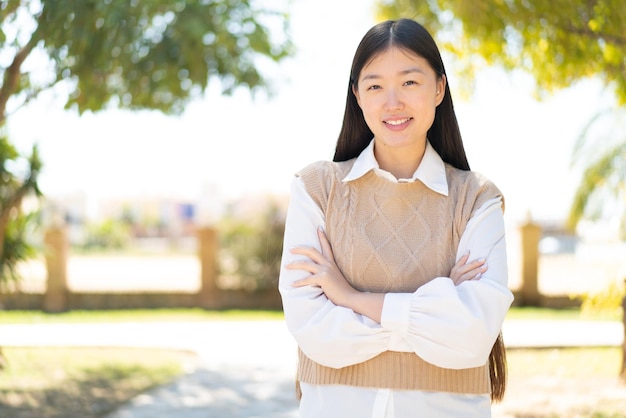 Mooie Chinese vrouw die buitenshuis de armen gekruist houdt in frontale positie