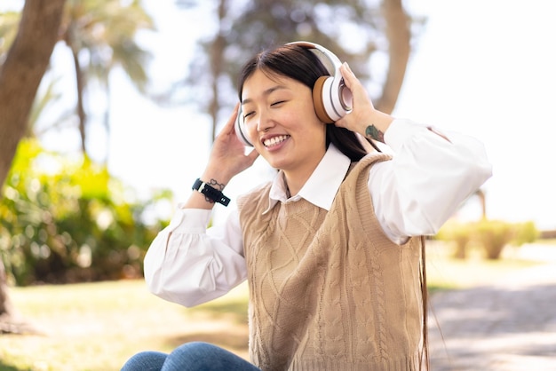 Mooie Chinese vrouw die buitenshuis muziek luistert