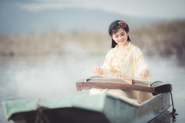 Mooie Chinese vrouw die en het traditionele Chinese muziekinstrument Boa zit speelt