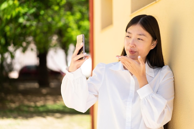 Mooie Chinese vrouw met behulp van mobiele telefoon buitenshuis