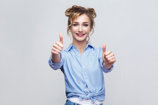 Mooie dame in blauw shirt duimen omhoog en kijken naar camera