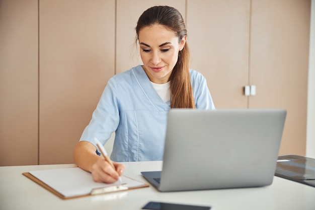 Mooie dame in medische scrubs aan het werk aan tafel