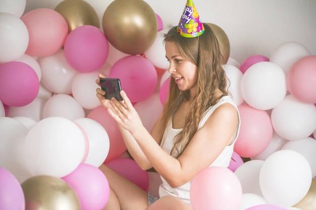 Mooie dame in pyjama selfie maken in haar slaapkamer met behulp van telefoon. fijne verjaardag.