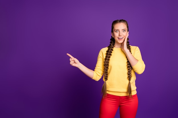 mooie dame lange vlechten vinger lege ruimte dragen casual gele trui rode broek geïsoleerde paarse kleur muur