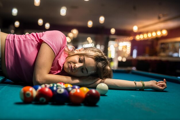 Mooie dame liggend op groene snookertafel onder de ballen. levensstijl