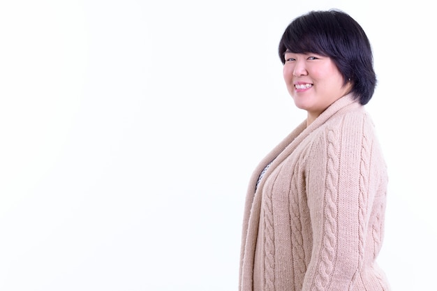 mooie dikke Aziatische vrouw met kort haar klaar voor de winter geïsoleerd tegen een witte muur