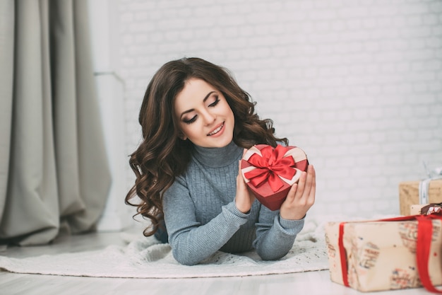 Mooie donkerbruine vrouw die een giftdoos houdt