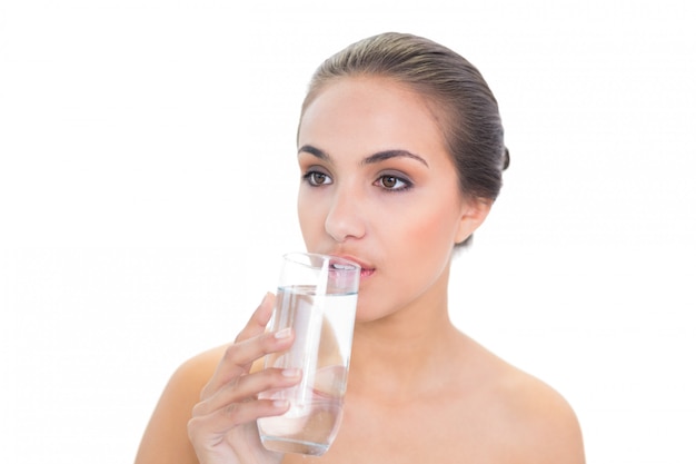 Mooie donkerbruine vrouw die een glas water drinkt