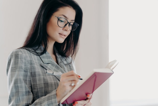 Mooie donkerbruine vrouw die in een blocnote schrijft