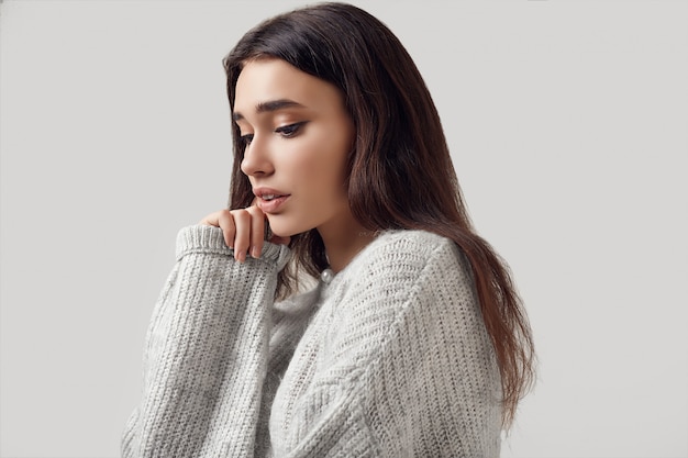 Mooie donkerbruine vrouw in sweater het stellen in studio