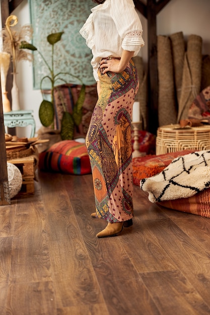 Mooie donkerharige vrouw in sjamanistische etnische outfit in bali-stijl ingerichte kamer