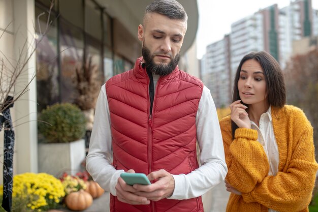 Mooie donkerharige vrouw kijkt vanaf de schouder terwijl ze haar vriend bespioneert