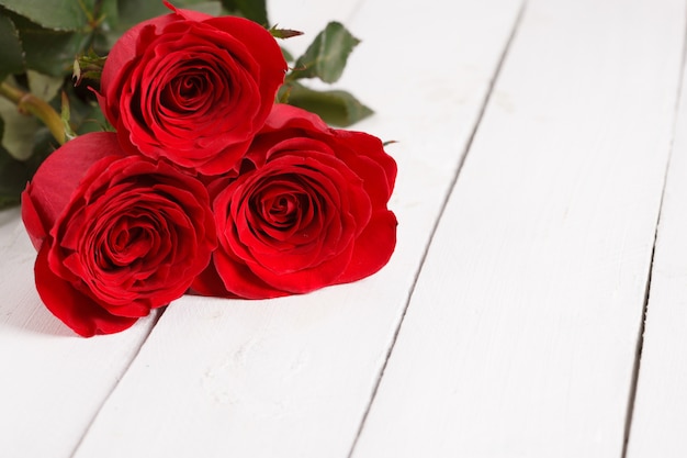 Mooie drie rode rozen op witte houten