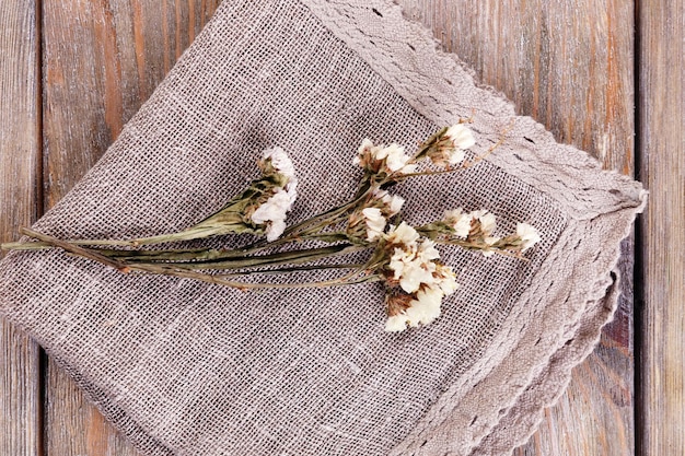 Foto mooie droge bloemen op servet op houten tafel close-up