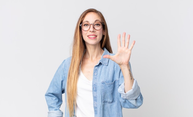 mooie dunne vrouw die lacht en er vriendelijk uitziet, nummer vijf of vijfde toont met de hand naar voren, aftellend