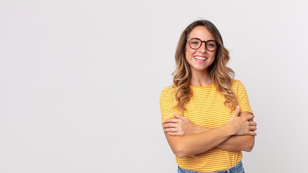 Mooie dunne vrouw die vrolijk lacht met gekruiste armen, met een ontspannen, positieve en tevreden pose