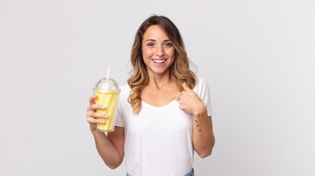 Mooie dunne vrouw die zich gelukkig voelt en naar zichzelf wijst met een opgewonden en een vanillemilkshake vast