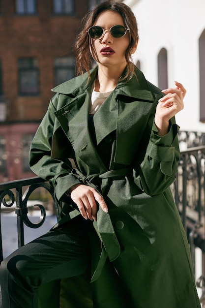 Mooie elegante donkerbruine vrouw die groene laag op het balkon draagt