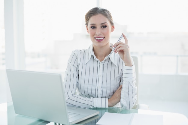 Mooie elegante onderneemsterzitting bij haar bureau die een potlood houden