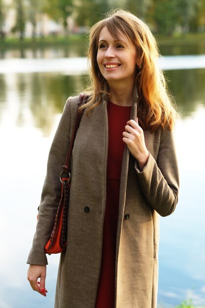 Mooie elegante vrouw die in de herfst in een park staat