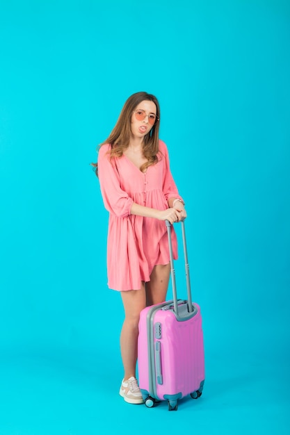 Mooie elegante vrouw in een roze jurk met een roze grote koffer voor op reis