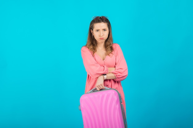 Mooie elegante vrouw in een roze jurk met een roze grote koffer voor op reis