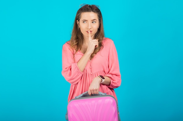 Mooie elegante vrouw in een roze jurk met een roze grote koffer voor op reis