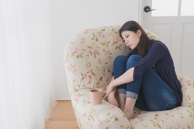 Foto mooie elegante vrouw zittend op een bankstoel in de woonkamer ontspannen wanneer ze zich moe voelt en pijnlijk ongemakkelijk wordt.