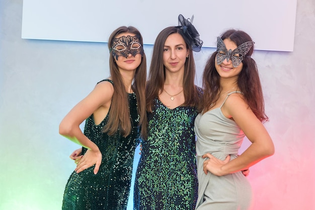 Mooie en aantrekkelijke vrouwen in maskerademaskers en elegante avondjurken poseren op een feestje