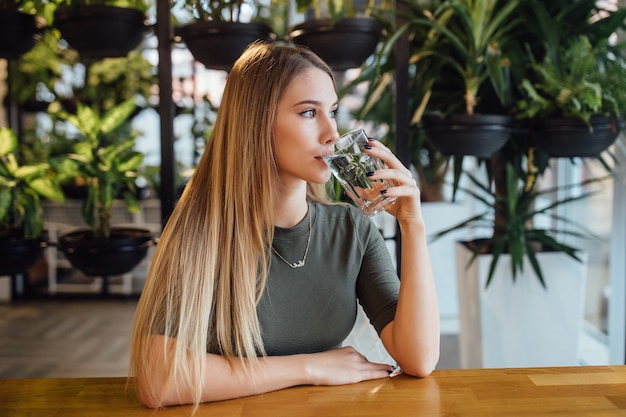 Foto mooie en blonde jonge vrouw met glas water in keuken