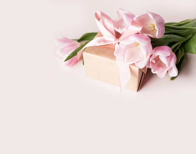 Mooie en delicate tulpans met een geschenk op een lichte achtergrond.