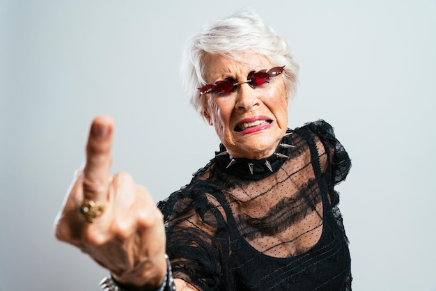 Mooie en elegante oude influencer vrouw. Cool grootmoeder poseren in studio modieuze kleding dragen. Gelukkige senior dame die feest viert en maakt. Concept over anciënniteit en levensstijl