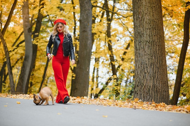 Mooie en gelukkige vrouw die geniet van wandelen in het park met haar schattige Franse bulldog