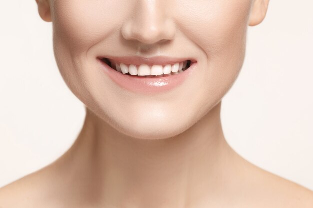Mooie en gezonde vrouwenglimlach, close-up op witte achtergrond