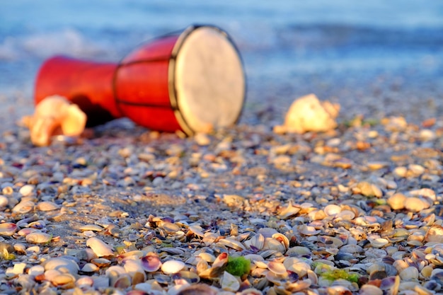 Mooie etnische trommel met schelpen op het strand op zonsopgangachtergrond