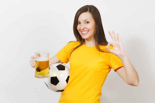 Mooie Europese jonge vrolijke vrouw, voetbalfan of speler in geel uniform met pint mok bier, voetbal geïsoleerd op een witte achtergrond. Sport, voetbal, gezond levensstijlconcept.