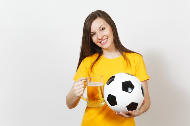 Mooie Europese jonge vrolijke vrouw, voetbalfan of speler in geel uniform met pint mok bier, voetbal geïsoleerd op een witte achtergrond. Sport, voetbal, gezond levensstijlconcept.