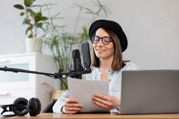 Mooie europese vrouw podcaster met koptelefoon en microfoon neemt podcast op in opname