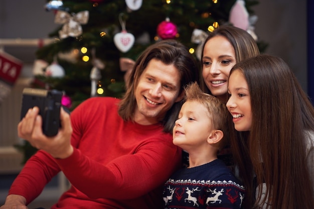 Mooie familie die Kerstmis thuis viert en direct foto's maakt