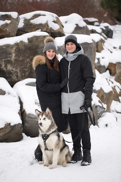 Mooie familie, een man en een meisje in het winterbos met hond. Speel met de hond Siberische husky.