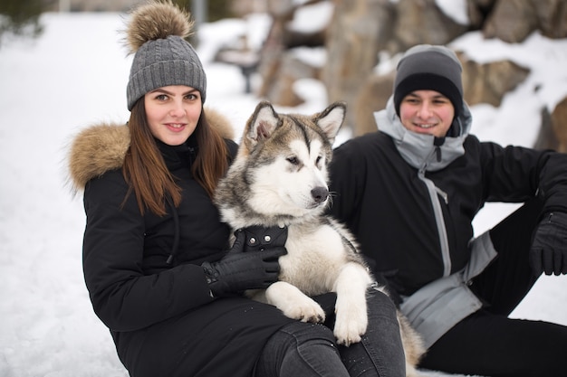 Mooie familie, een man en een meisje in het winterbos met hond. Speel met de hond Siberische husky.