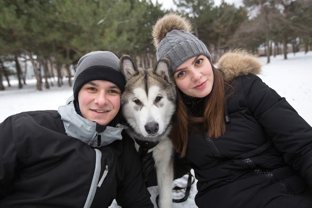 Mooie familie, een man en een meisje in het winterbos met hond. Speel met de hond Siberische husky.