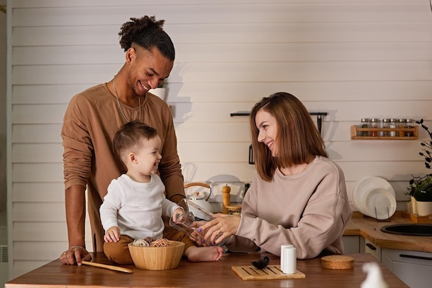 Mooie familie in gezellige bruine kleren zittend aan een tafel in de keuken