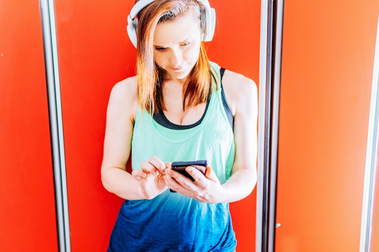 Mooie fit jonge vrouw die sociale media in de kleedkamer van de sportschool controleert. sport- en technologieconcept
