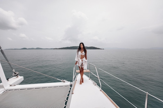 Mooie fit meid is een witte mooie bikini poseert op jacht en er is een water op de achtergrond