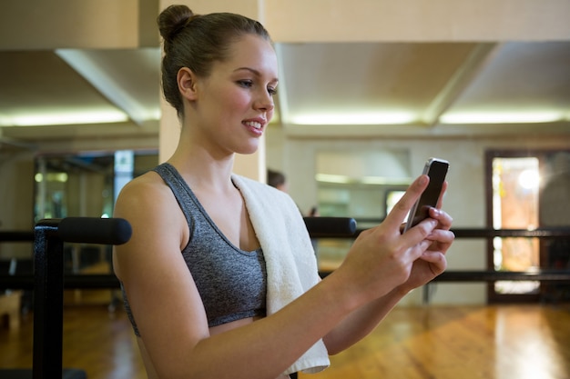 Mooie fit vrouw met behulp van mobiele telefoon na training